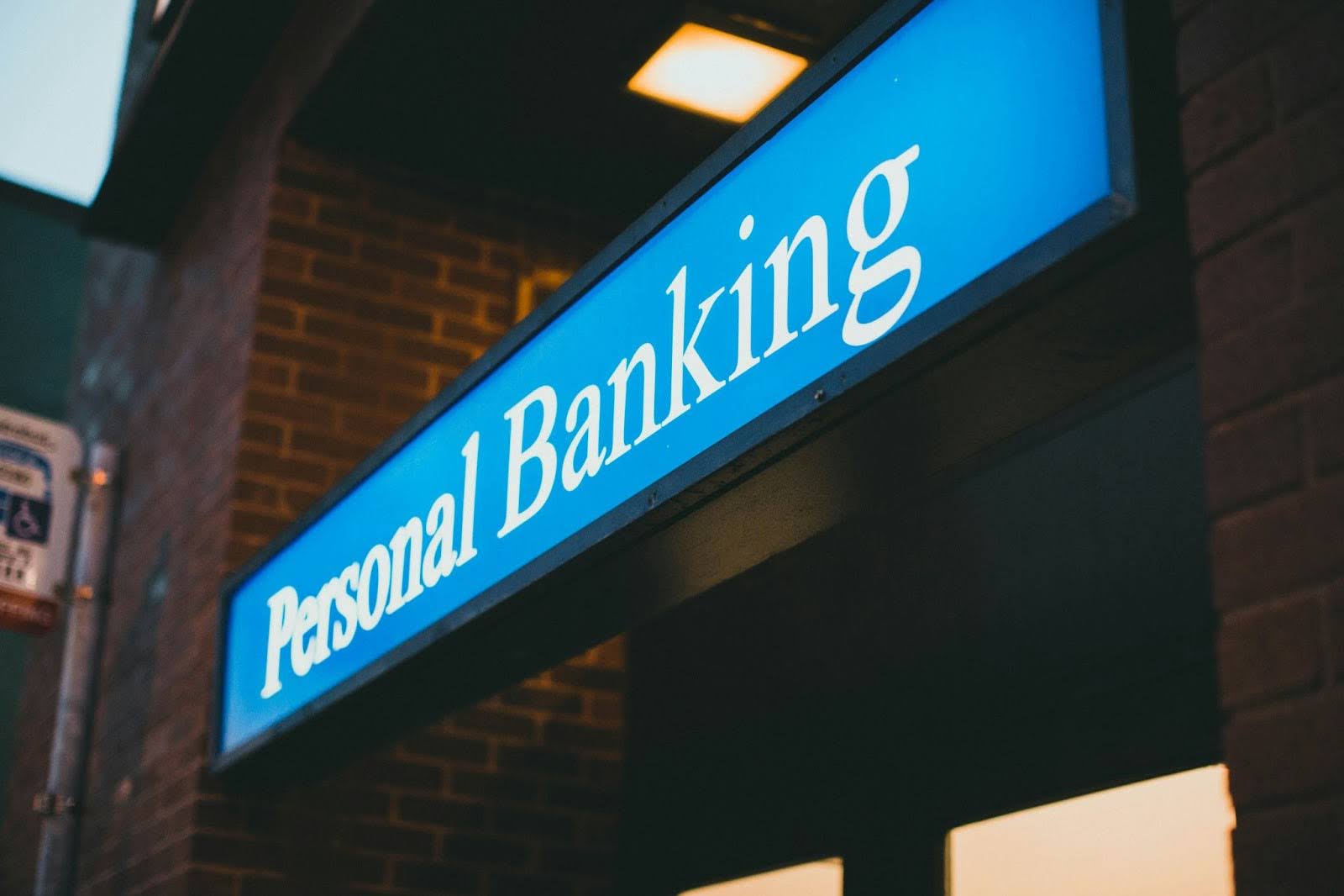  Personal banking today means more than a branch; it means knowing your account holders and delivering what matters most. Source: Photo by Jonathan Cooper on Unsplash. Alt text: Illuminated 'Personal Banking' sign outside a brick building, photographed at dusk