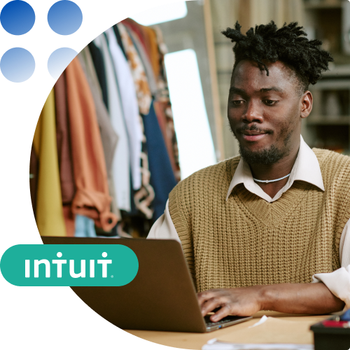 Man with curly hair in a beige sweater uses a laptop in a clothing shop, with an Intuit logo overlay in the corner.