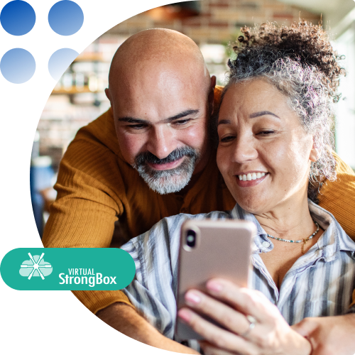 Two adults smile as they look at a smartphone together, with a teal Virtual StrongBox badge in the lower-left corner.